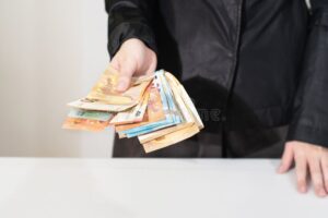 mani che scambiano una banconota tra di loro