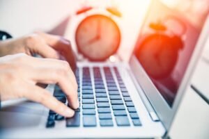 orologio e mani che lavorano al computer