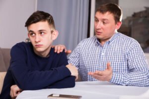 padre e figlio discutono davanti casa familiare